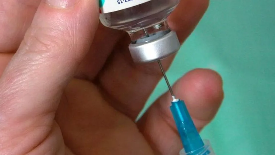 주사기로 백신 병에서 약을 뽑는 모습