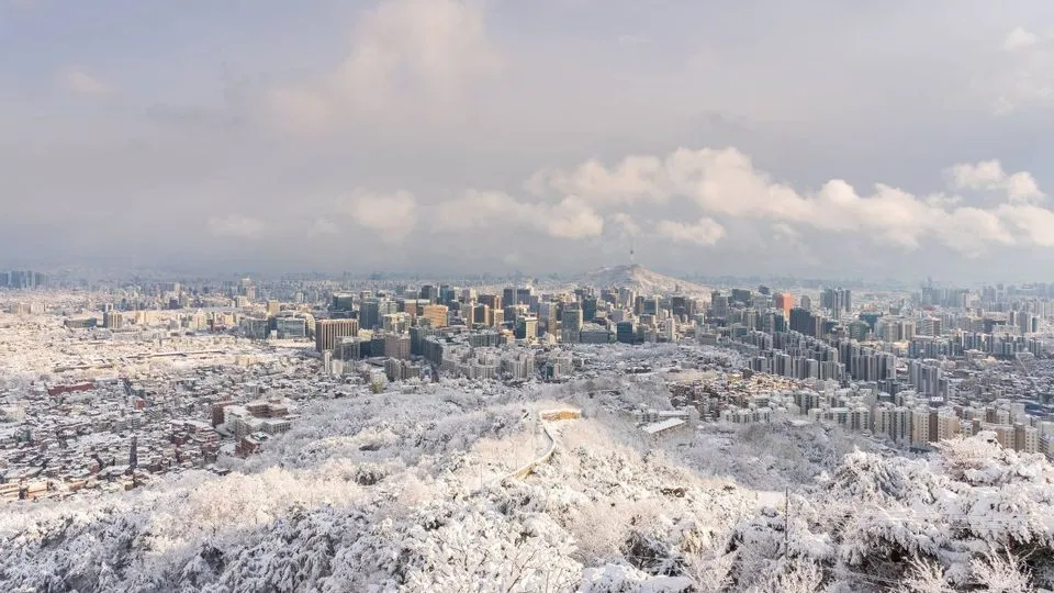 눈 덮인 산 너머로 보이는 겨울 서울 도심 전경